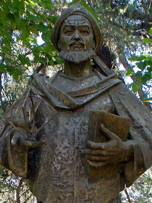 Estátua de pedra de al-Khwarizmi sentado, com um livro, em frente a um prédio universitário em Madri.