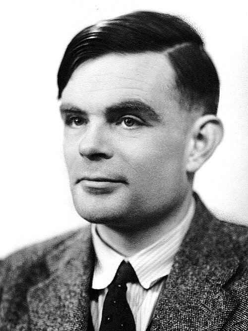 Fotografia em preto e branco de Alan Turing jovem, de terno e gravata.